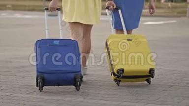 旅客携带行李箱在火车站站台行走.. 两个拿着行李的女人去机场
